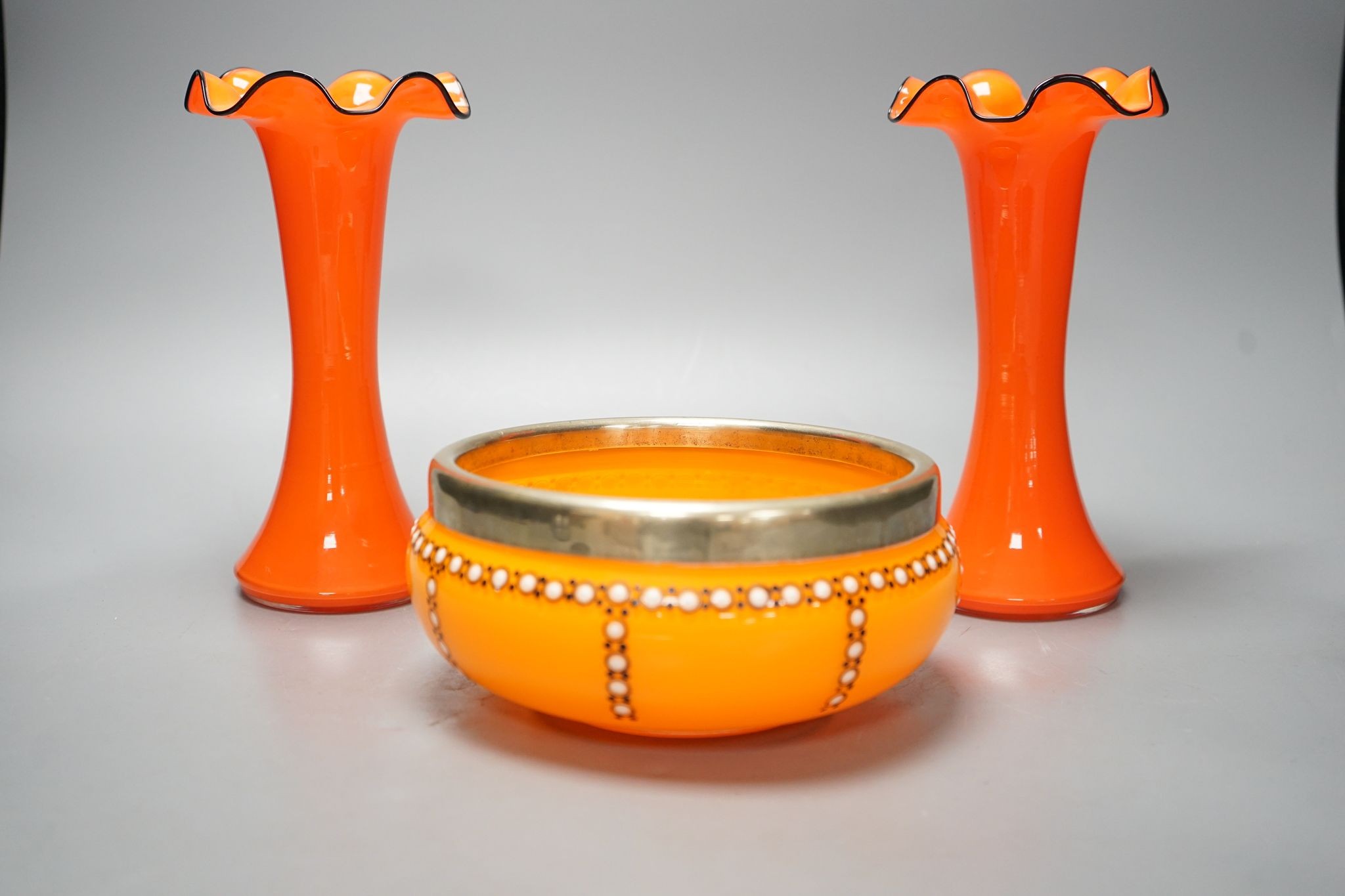 A tangerine glass bowl with silver plated mount to rim and a pair of spill vases, in the style of Michael Powdry, tallest 21cm
